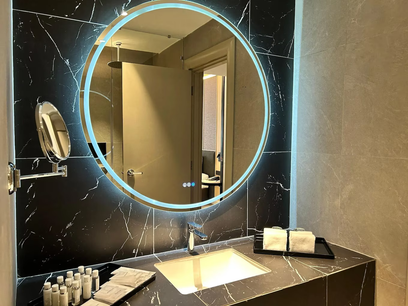 Completed hotel vanity with illuminated round mirror and stone finish